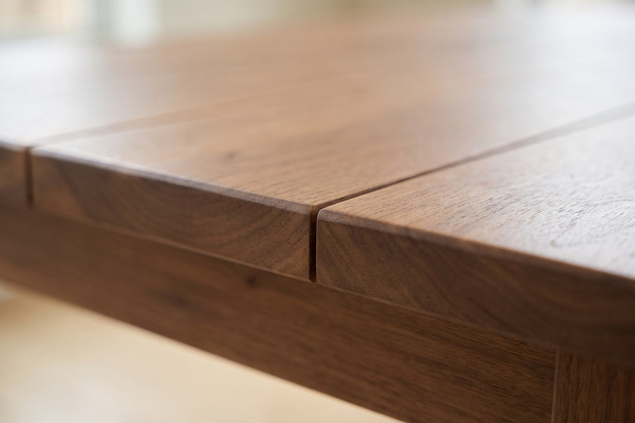 Sète Walnut Plank Dining Table: close-up of the fine joint between two walnut planks on the top and its gently eased edge, grain visible