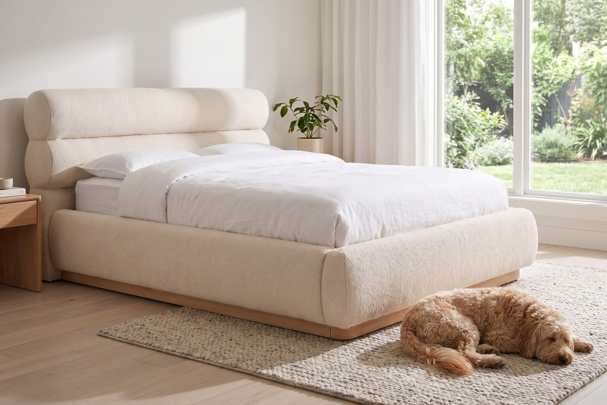 Valloire Ivory Bouclé Bed, side view by a garden window, a dog asleep beside the bed