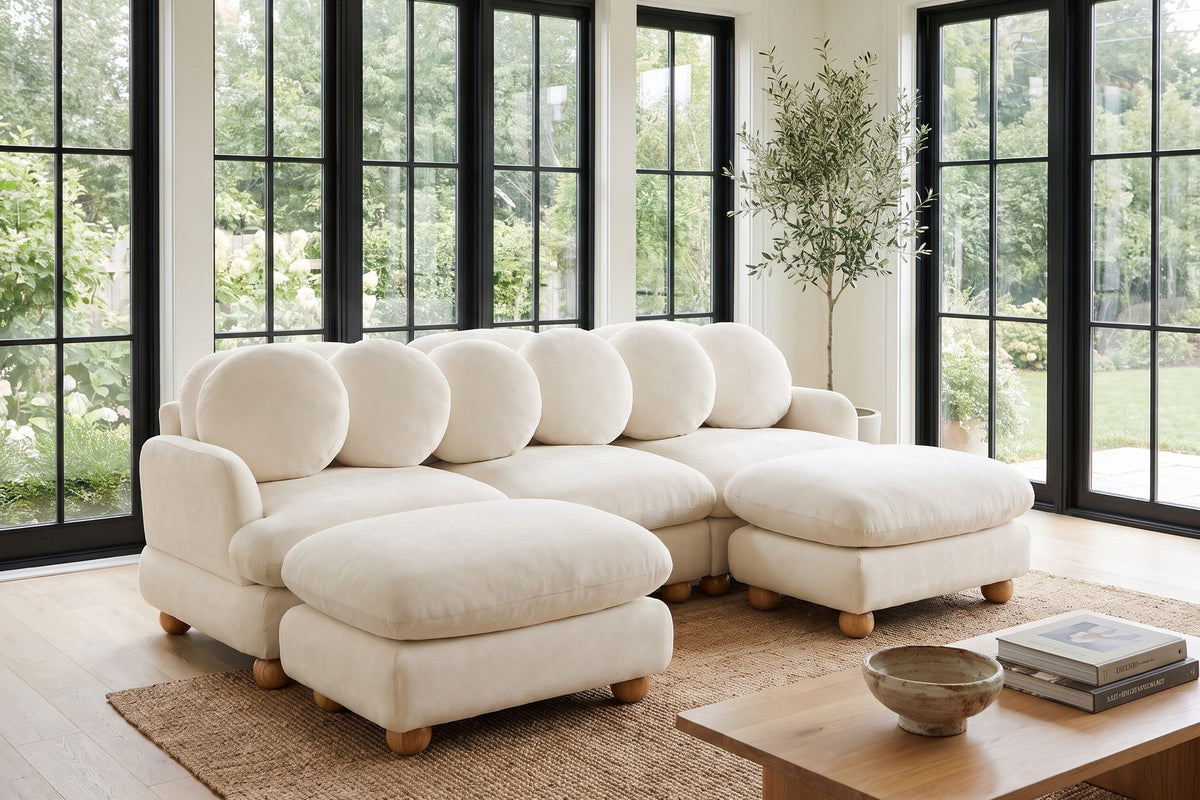 By tall garden windows, the round wood feet keep the cream chenille just off the floor.