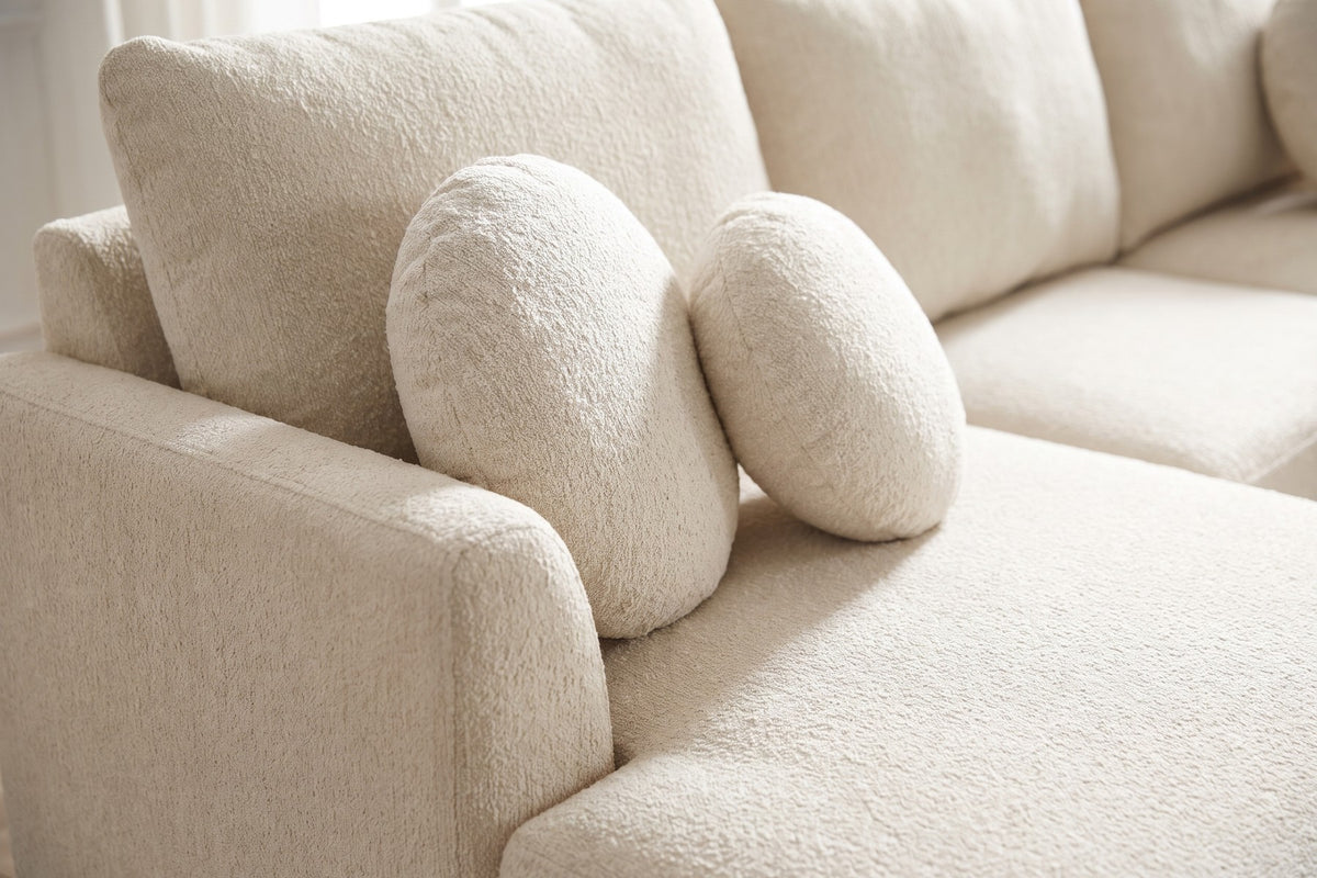 Close-up of two round cream chenille pillows against a back cushion, beside the low rounded arm, showing the soft chenille texture (Vaugirard)