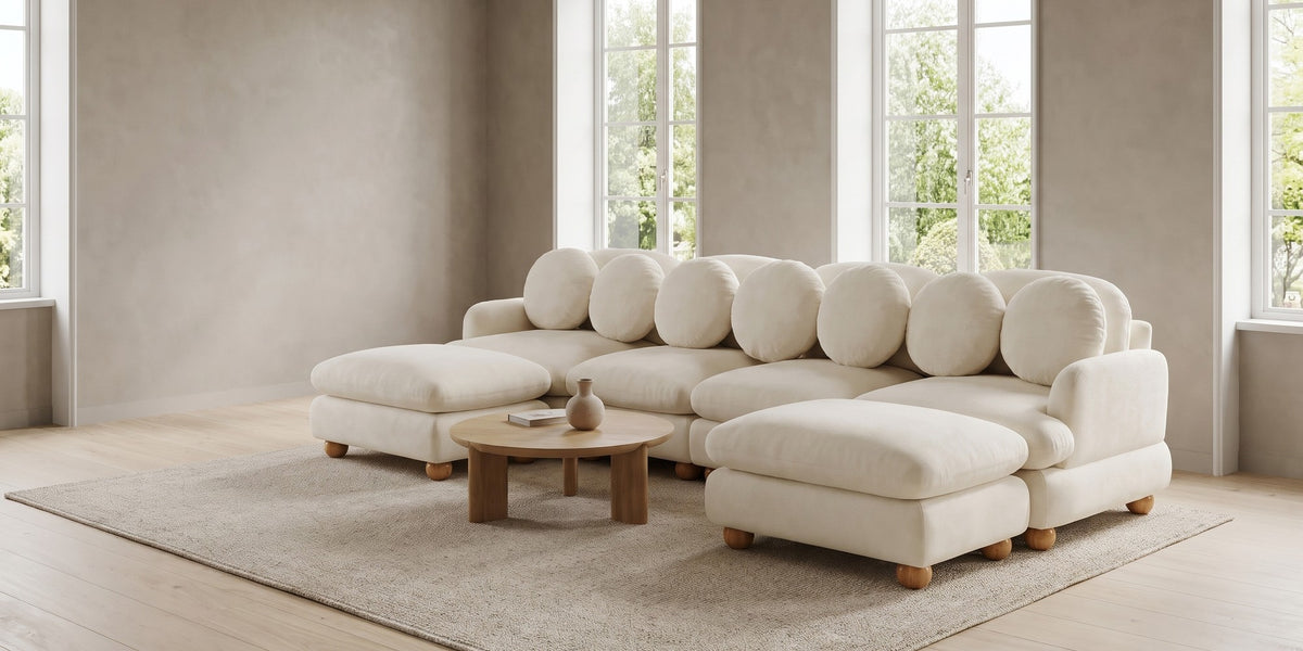 Vaugirard cream chenille modular u-sectional with round pillows and wood ball feet in a wide room view