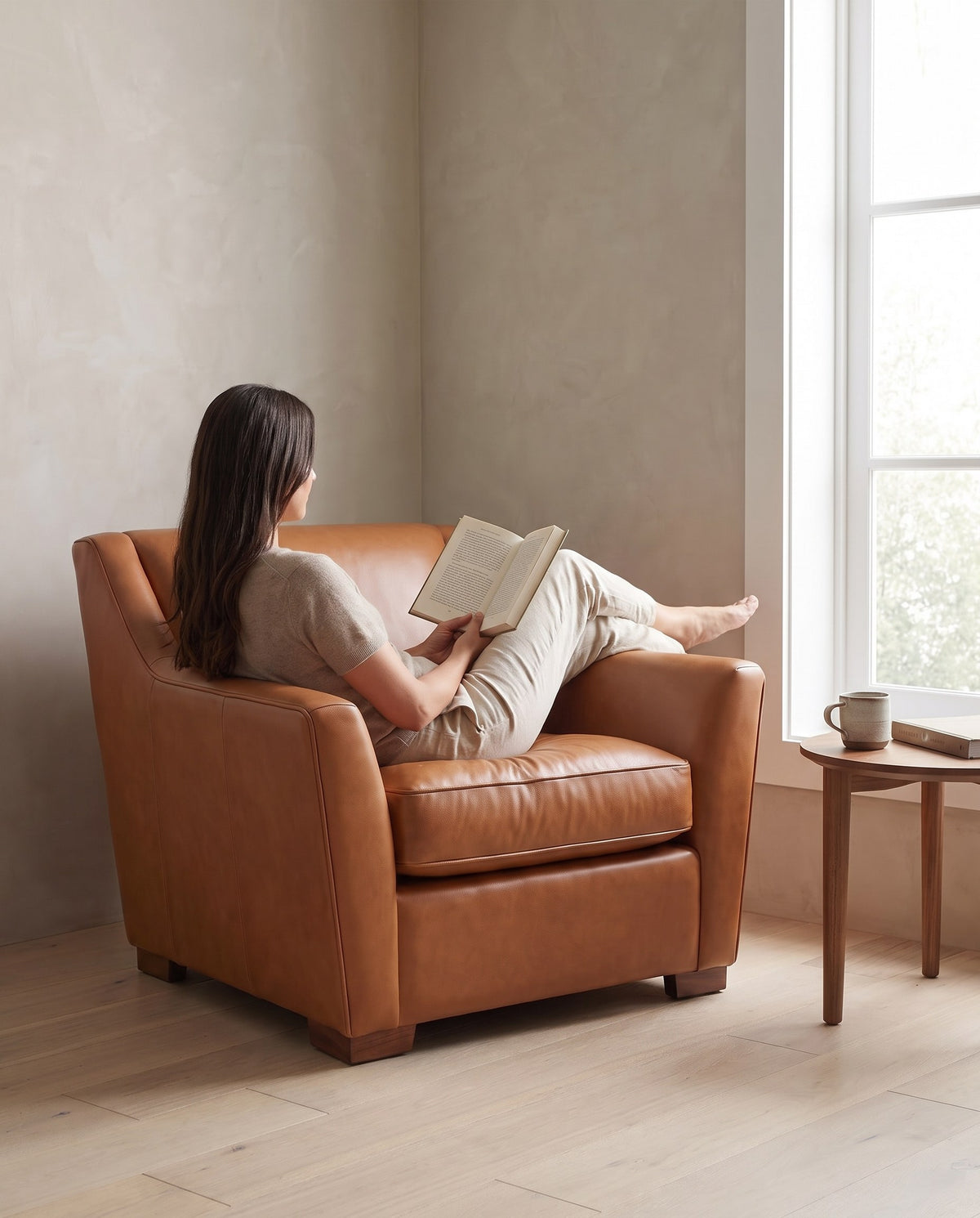 A person reading in the Vence cognac leather lounge chair (concept image)