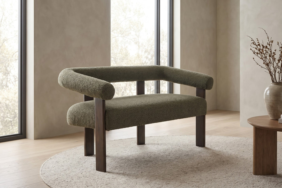 By a tall window, the green bouclé bolsters rest on brown rubberwood legs.